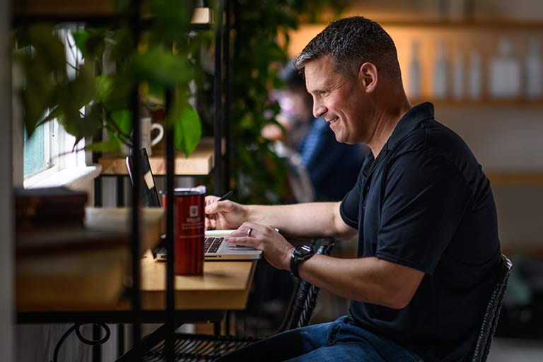 Online MBA student works on computer in a cafe