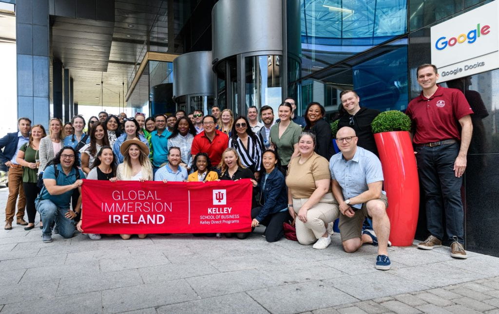 A group of Kelley Direct Online MBA students hold the "Global Immersion: Ireland" flag outside of Google's offices in Ireland.